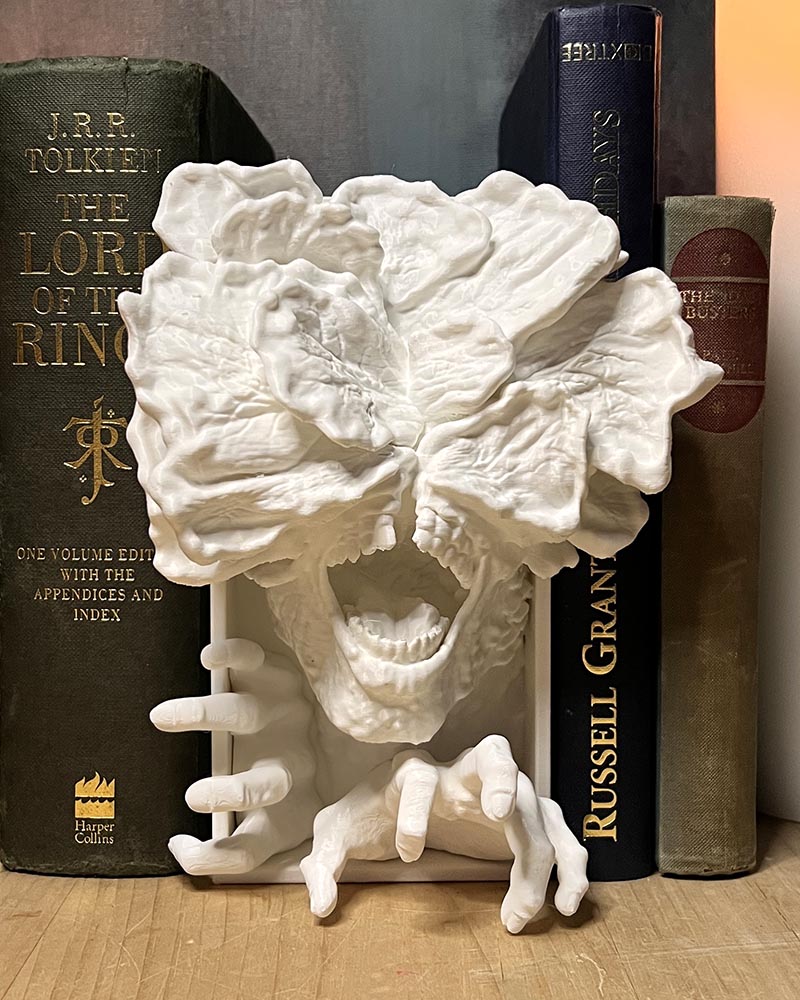White 3D printed fantasy creature book nook sitting between books  on a shelf — Loonar 3D bookshelf insert