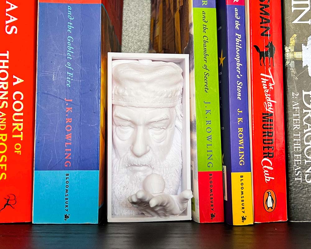 Dumbledore book nook holding Golden Snitch 3D printed Harry Potter book nook wizarding shelf insert Magical bookshelf décor featuring Dumbledore figure Fantasy book nook with Dumbledore and Snitch design Wizarding world book nook gift for Harry Potter fans