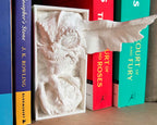Side view of mischievous gremlin shelf insert between books