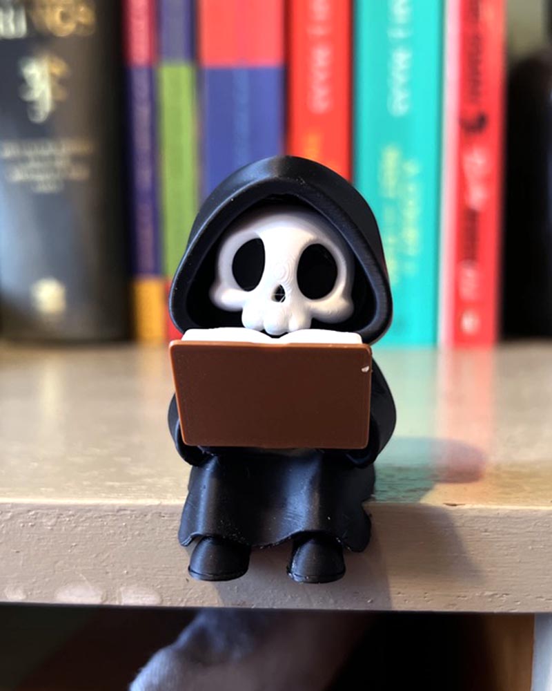 3d printed cute grim reaper figurine sitting on shelf ledge booksit shelf decor