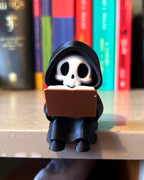 3d printed cute grim reaper figurine sitting on shelf ledge booksit shelf decor