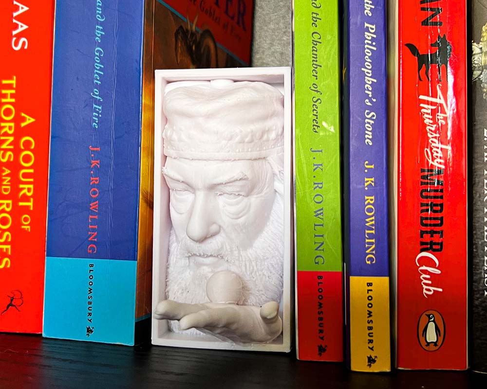 Dumbledore book nook holding Golden Snitch 3D printed Harry Potter book nook wizarding shelf insert Magical bookshelf décor featuring Dumbledore figure Fantasy book nook with Dumbledore and Snitch design Wizarding world book nook gift for Harry Potter fans