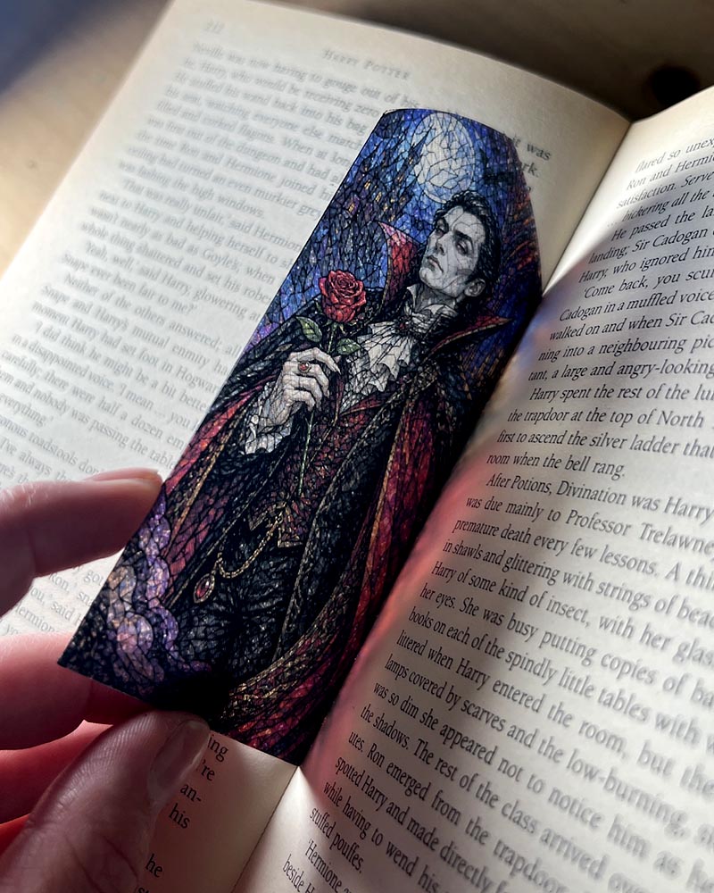 Gothic stained glass window bookmark featuring an elegant vampire holding a red rose beneath a moonlit blue sky.