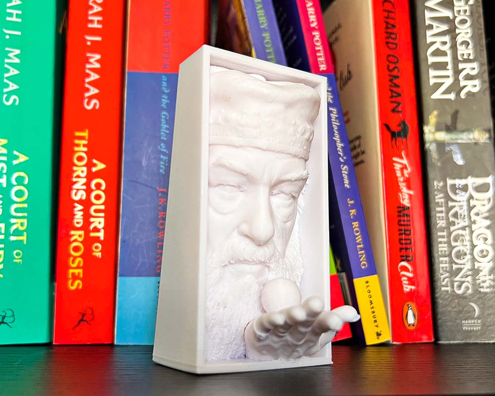 Dumbledore book nook holding Golden Snitch 3D printed Harry Potter book nook wizarding shelf insert Magical bookshelf décor featuring Dumbledore figure Fantasy book nook with Dumbledore and Snitch design Wizarding world book nook gift for Harry Potter fans